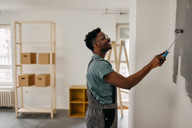 African-American professional painter paints the wall indoors